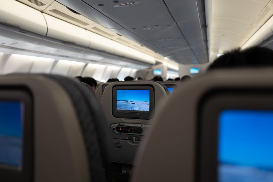 Interior of an airplane displaying in-flight entertainment screens and passenger seats.