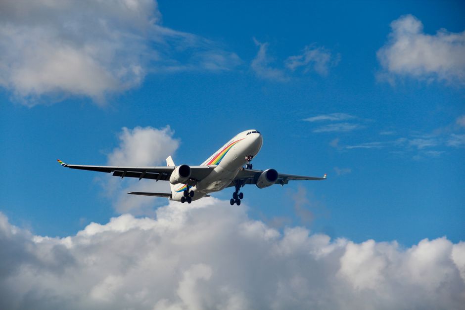 An airplane in flight against a vibrant blue sky filled with clouds, showcasing air travel.